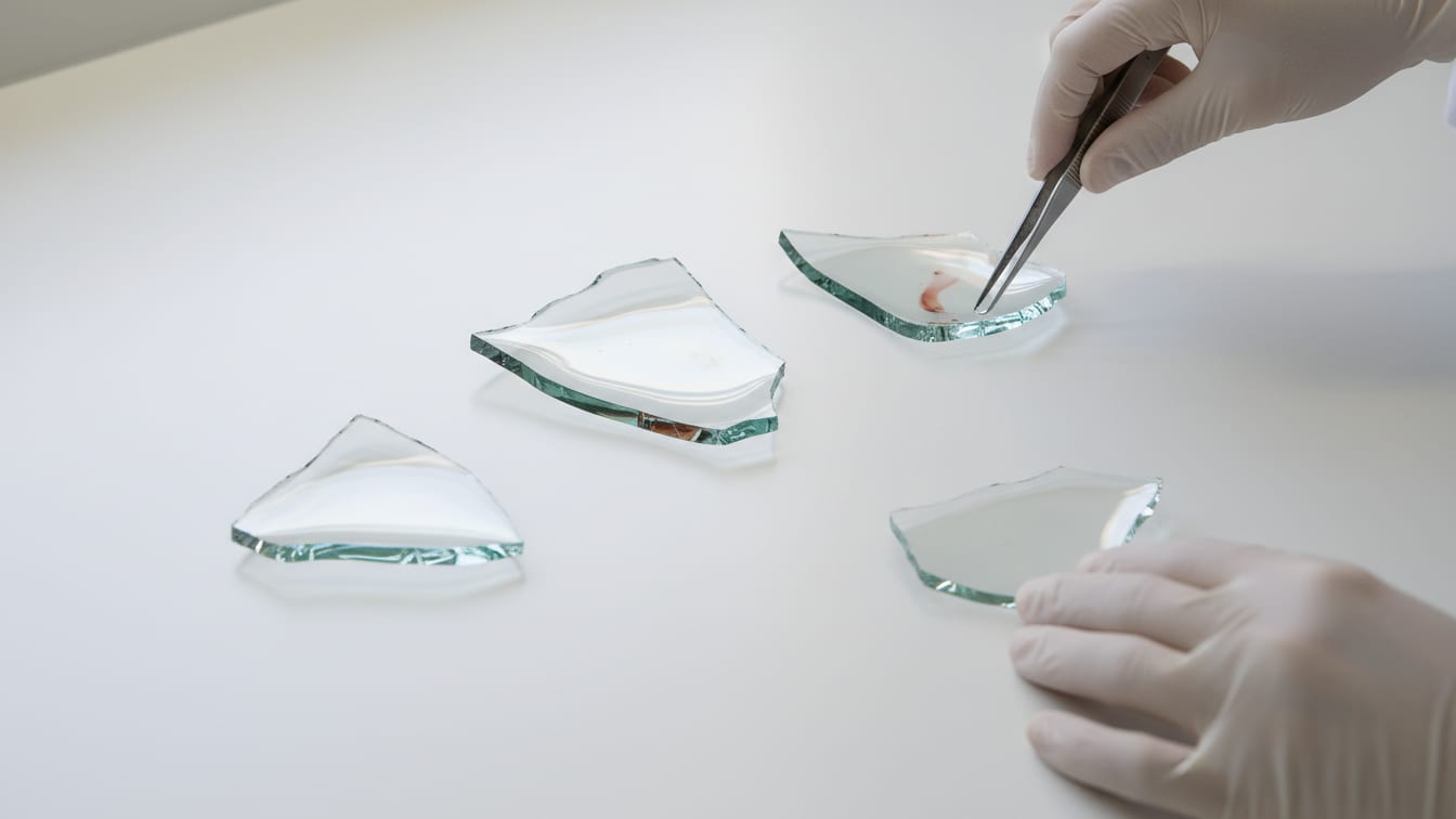Illustration: Three clear glass fragments on a white lab bench.