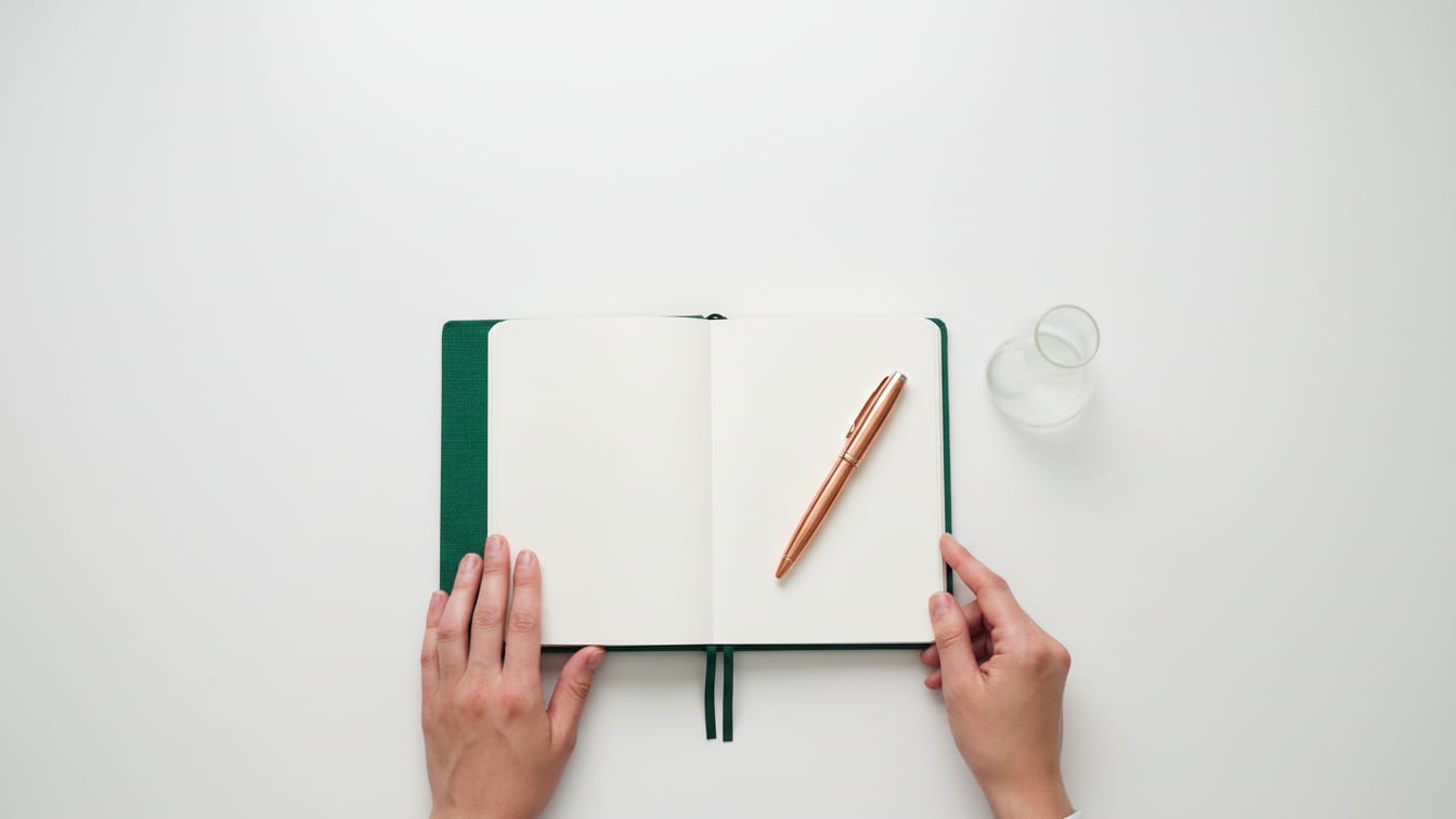 Illustration: An open notebook, fountain pen, and beaker on a white lab bench.