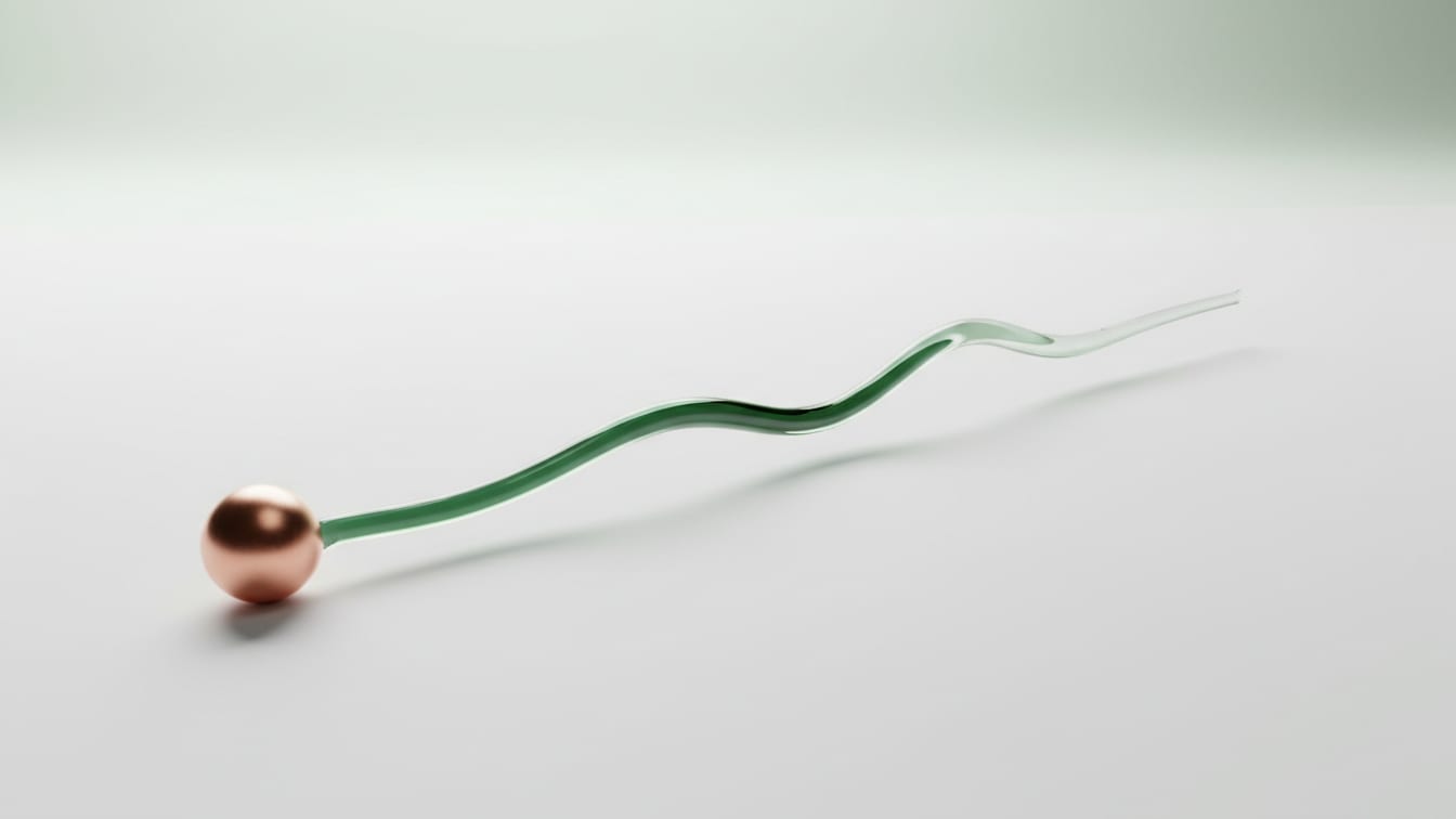 Illustration: A translucent glass rod with a green core and a copper sphere on a white surface.
