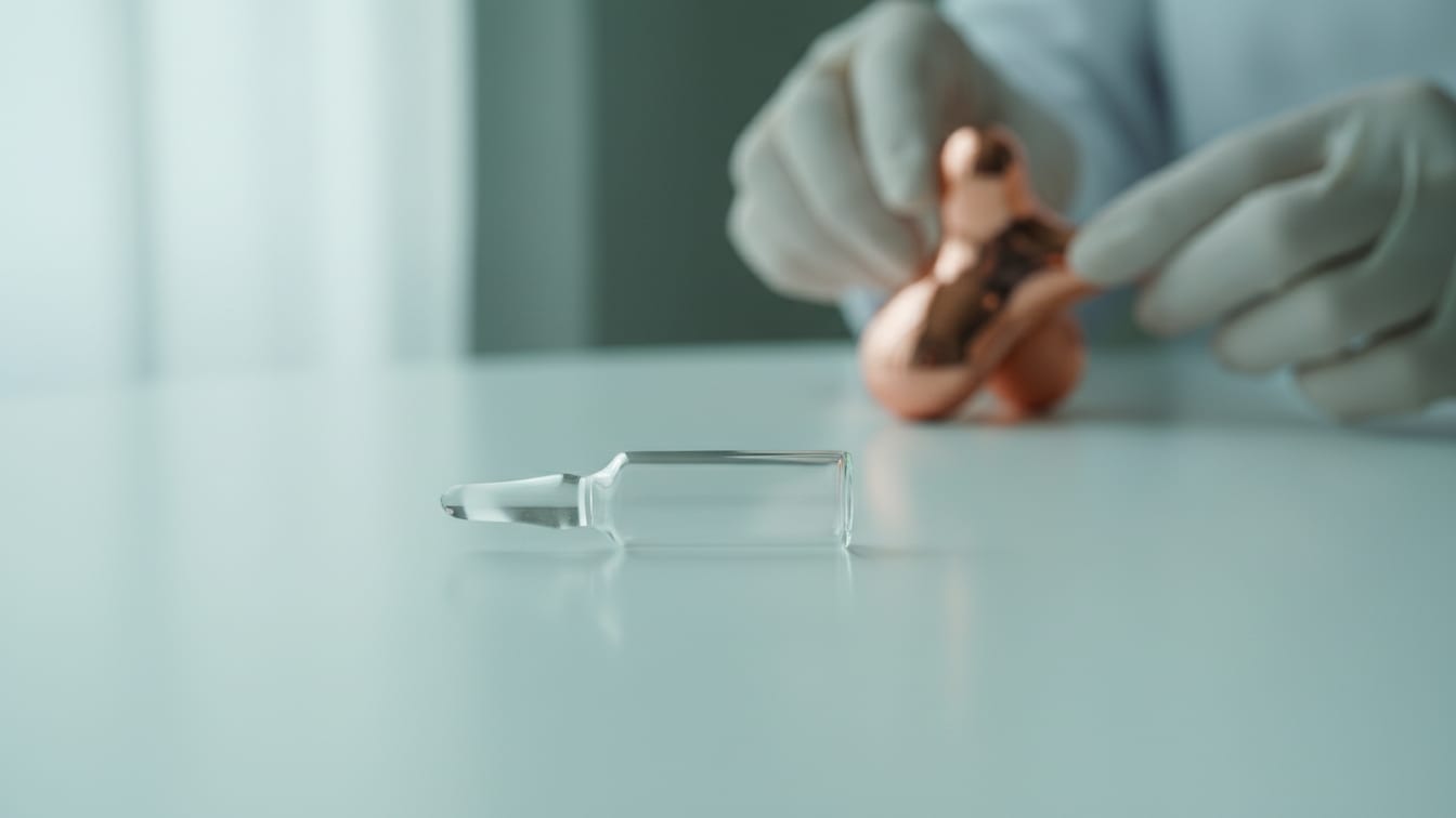 Illustration: An empty, clear glass ampule on a white surface with a subtle green reflection.